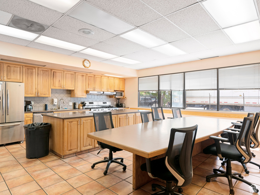Kitchen with decorative backsplash, light brown cabinets, a sink, and appliances with stainless steel finishes