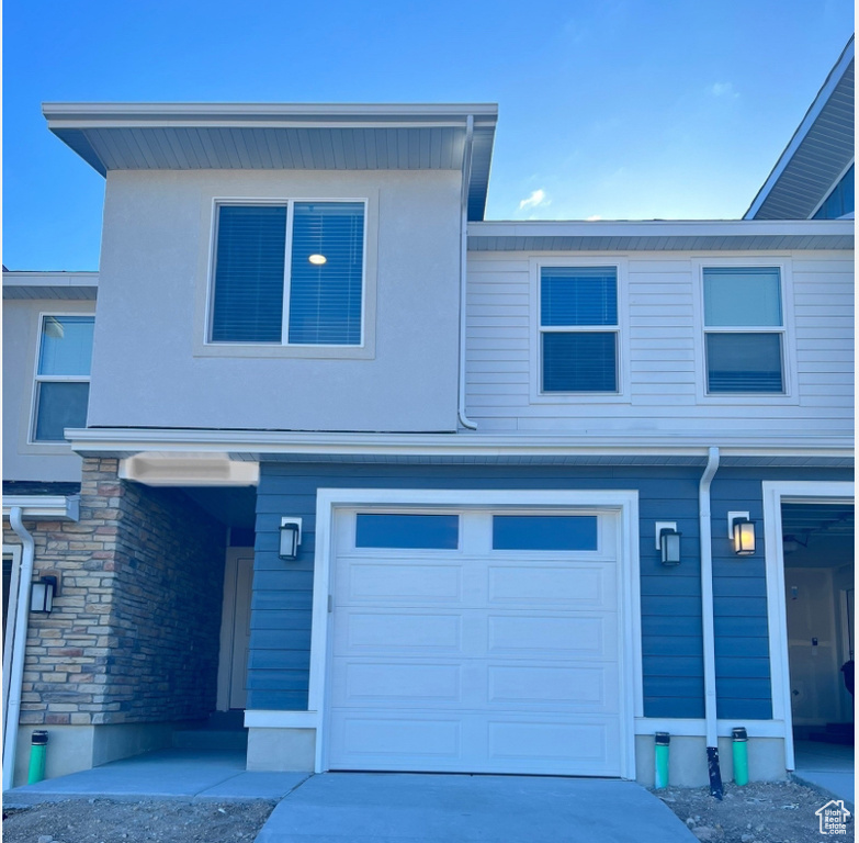 View of front facade featuring stone siding, an attached garage, and driveway