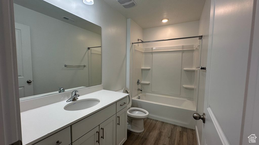 Full bath featuring visible vents, toilet, wood finished floors, vanity, and  shower combination