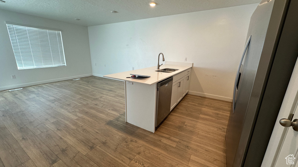 Kitchen with wood finished floors, a peninsula, a sink, and stainless steel appliances
