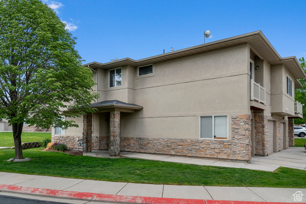 View of front of home featuring stone siding, stucco siding, a front lawn, and a garage