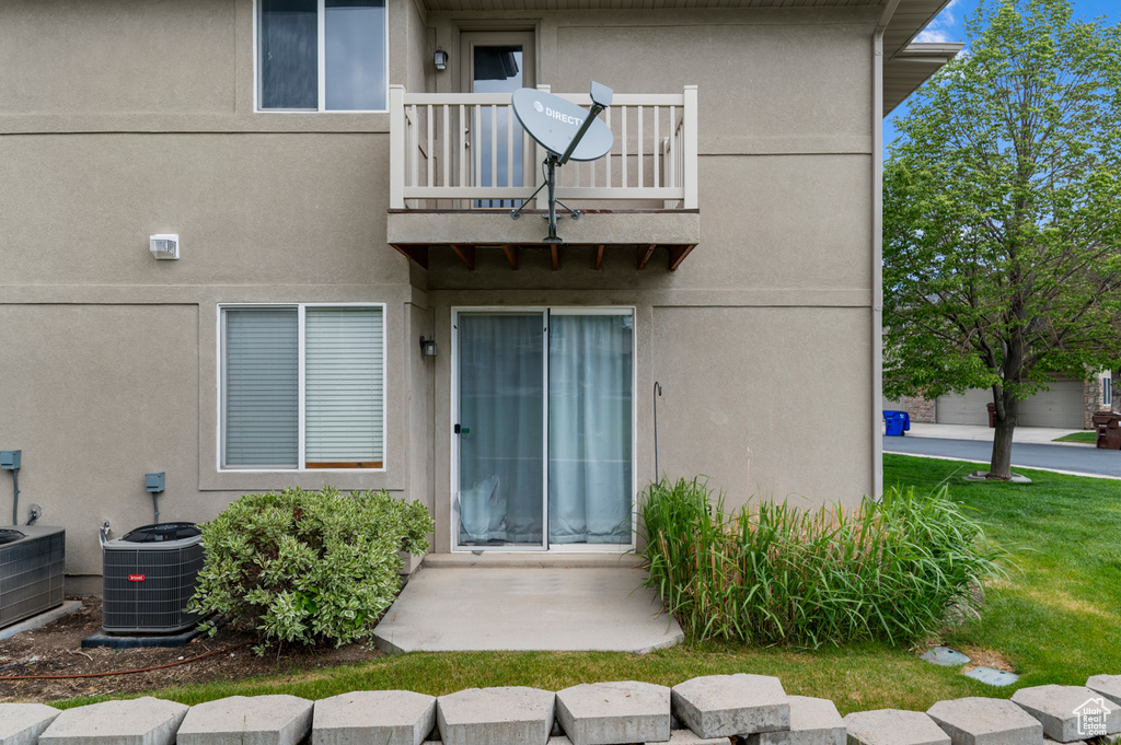 Property entrance with a balcony, cooling unit, and stucco siding