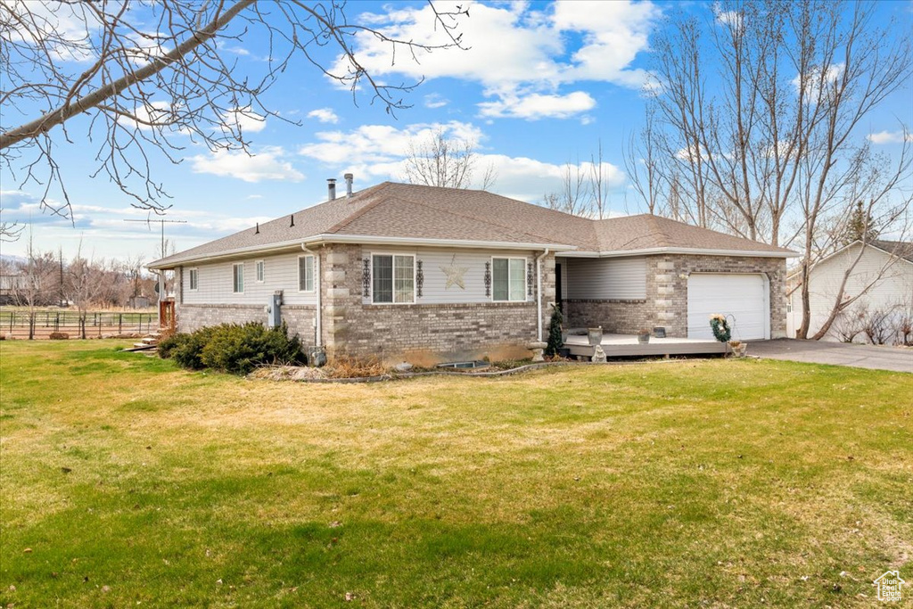 Ranch-style house with driveway, fence, an attached garage, brick siding, and a front lawn