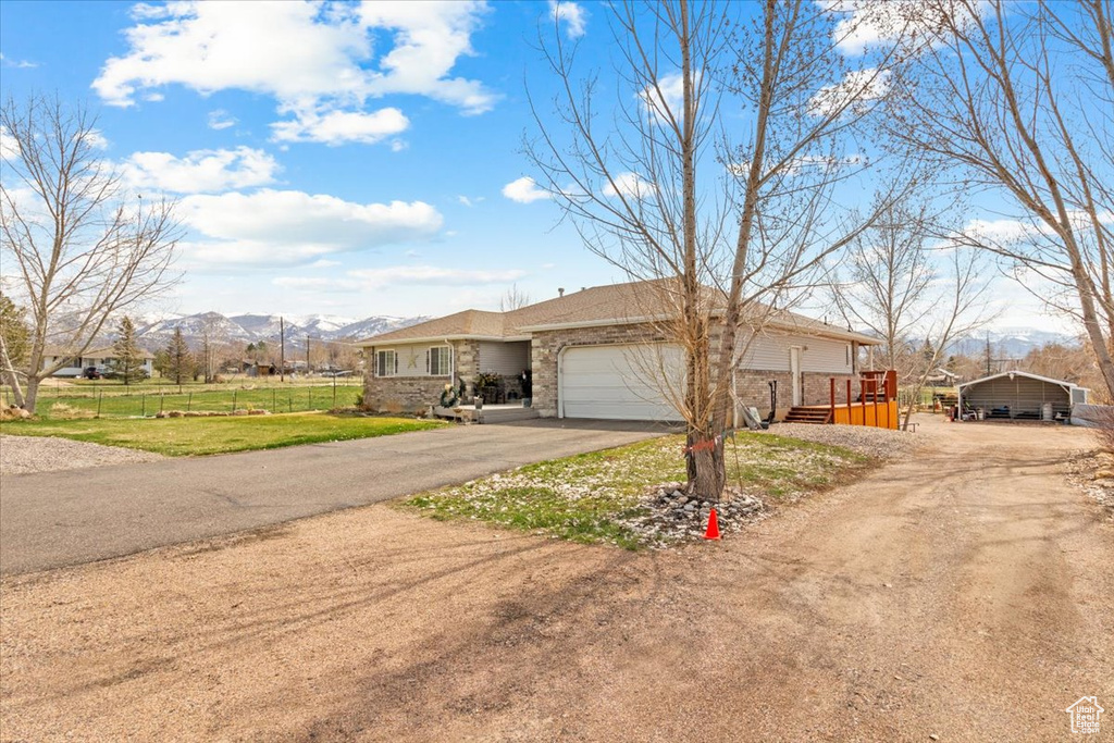 View of front of property with driveway, a mountain view, fence, and an attached garage