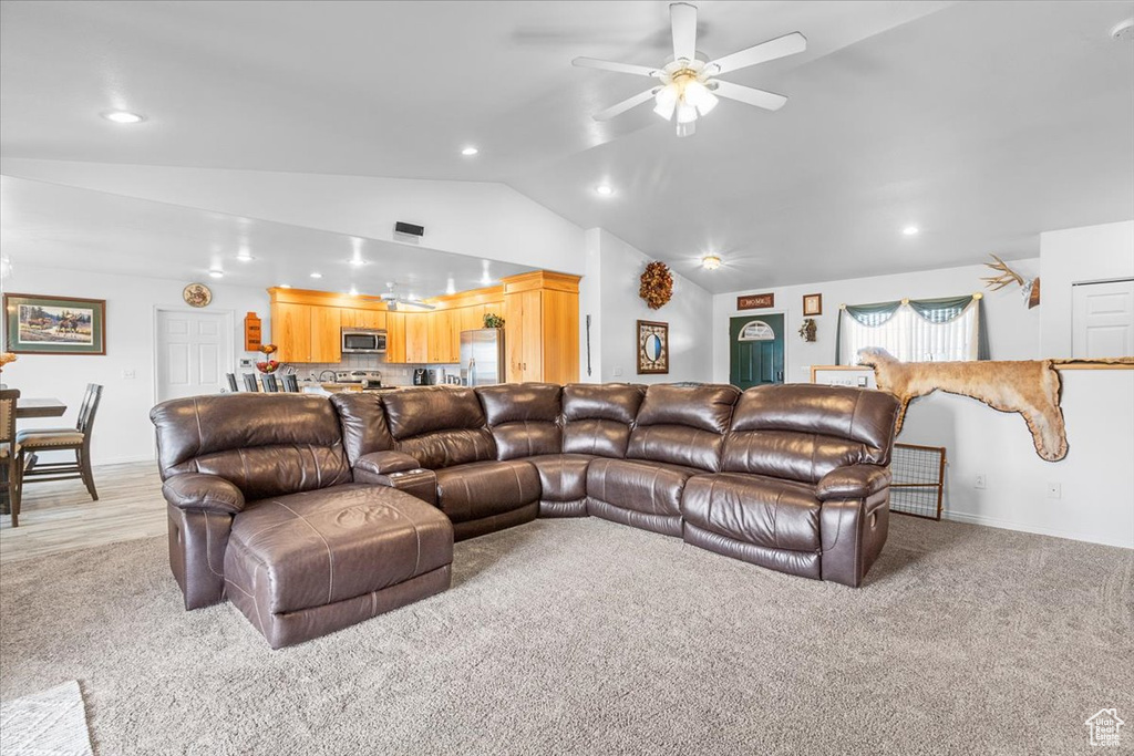 Living room with lofted ceiling, recessed lighting, a ceiling fan, and light carpet