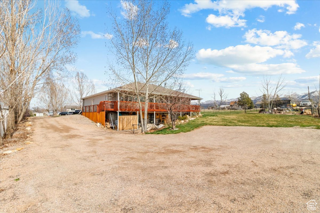 Exterior space featuring a lawn, a wooden deck, and dirt driveway
