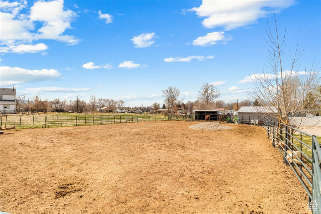 View of yard featuring an exterior structure, an outdoor structure, a rural view, and an enclosed area