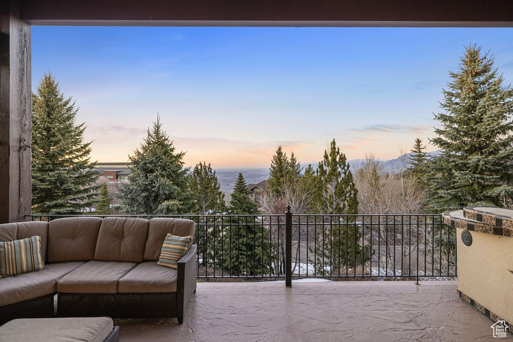 Patio terrace at dusk featuring an outdoor living space and a balcony