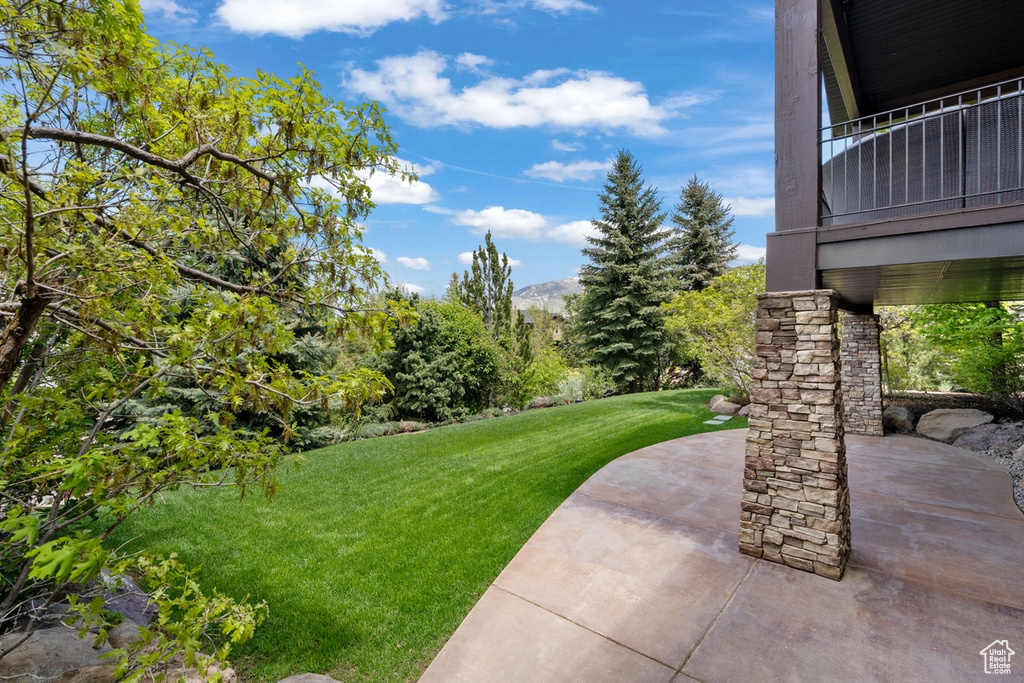 View of green lawn with a patio and a mountain view