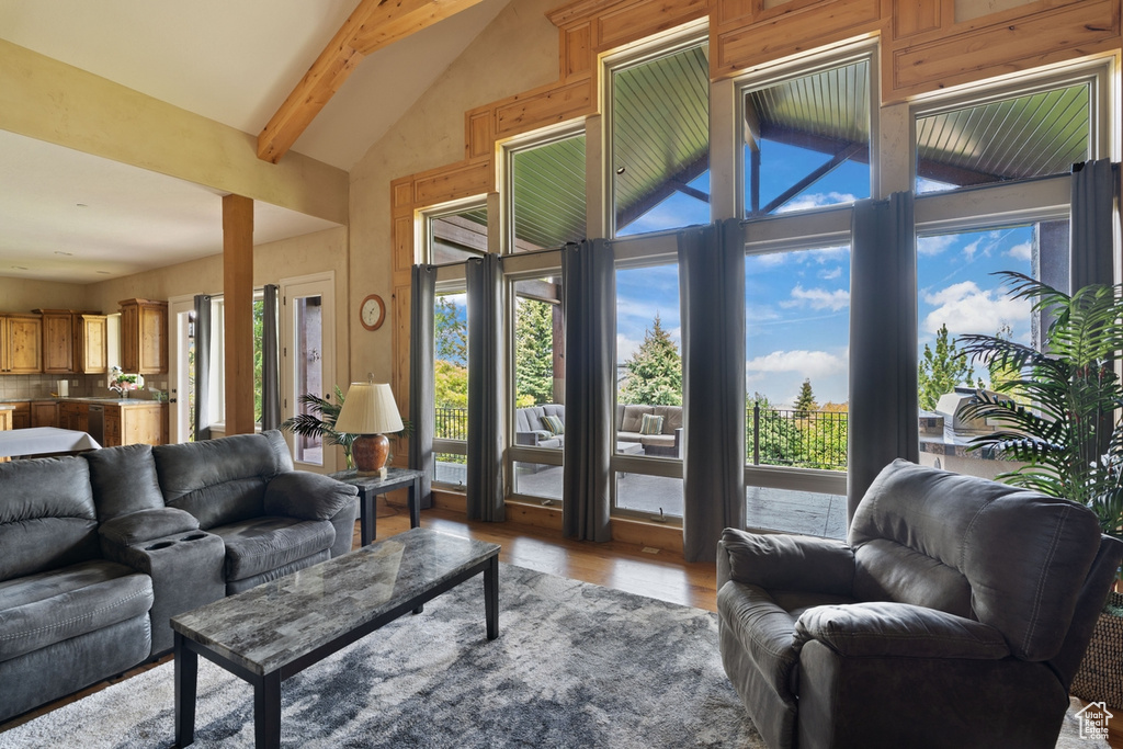 Living area featuring wood finished floors, plenty of natural light, beamed ceiling, and high vaulted ceiling