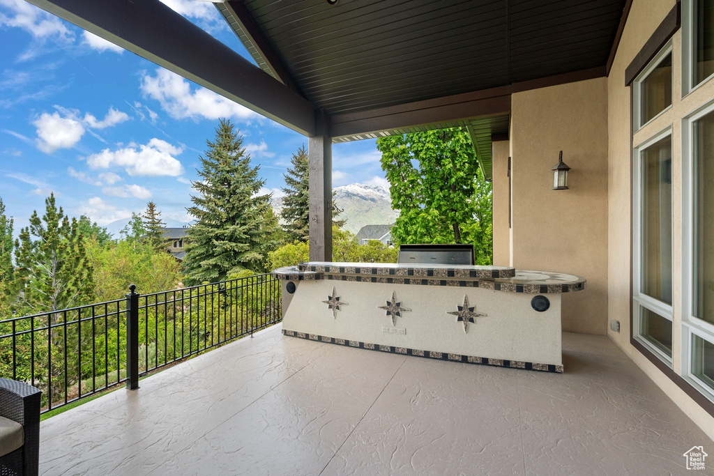 View of patio featuring exterior kitchen and a balcony