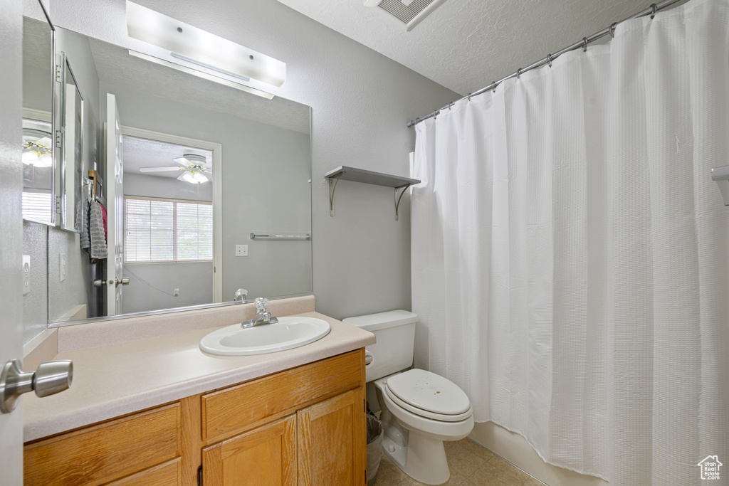 Full bath featuring toilet, vanity, a ceiling fan, a textured ceiling, and visible vents