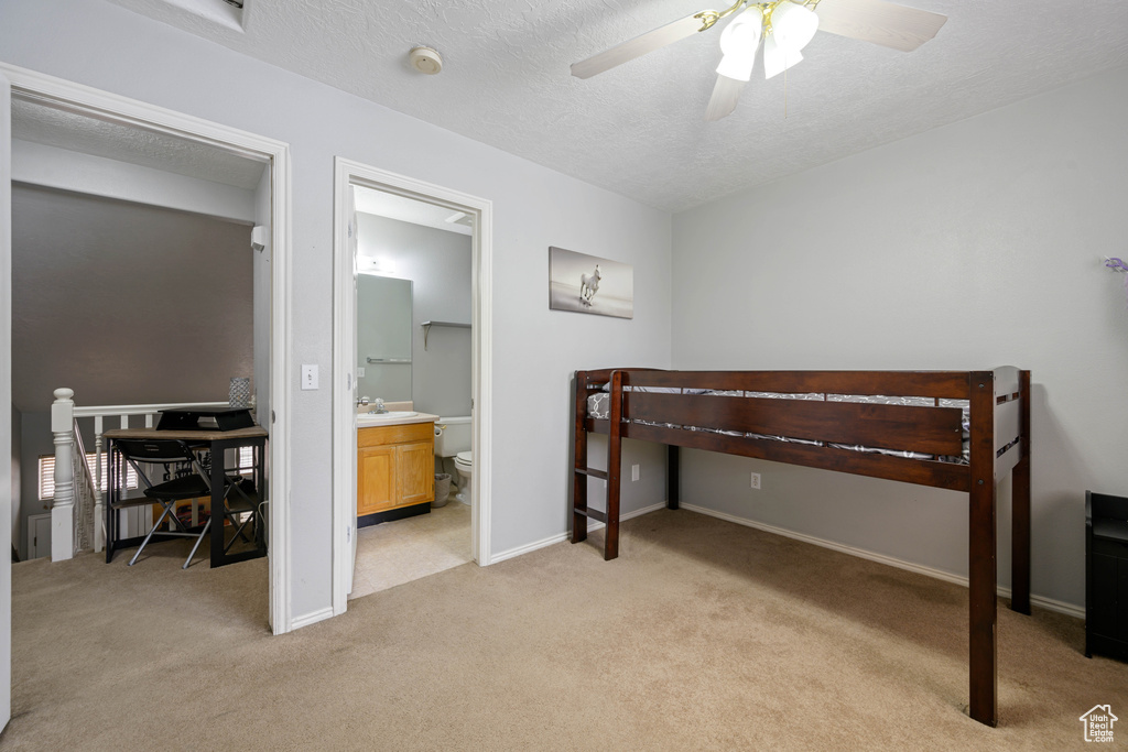 Bedroom featuring baseboards, a textured ceiling, ensuite bathroom, and light carpet