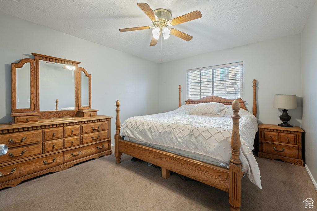 Bedroom with carpet, ceiling fan, and a textured ceiling