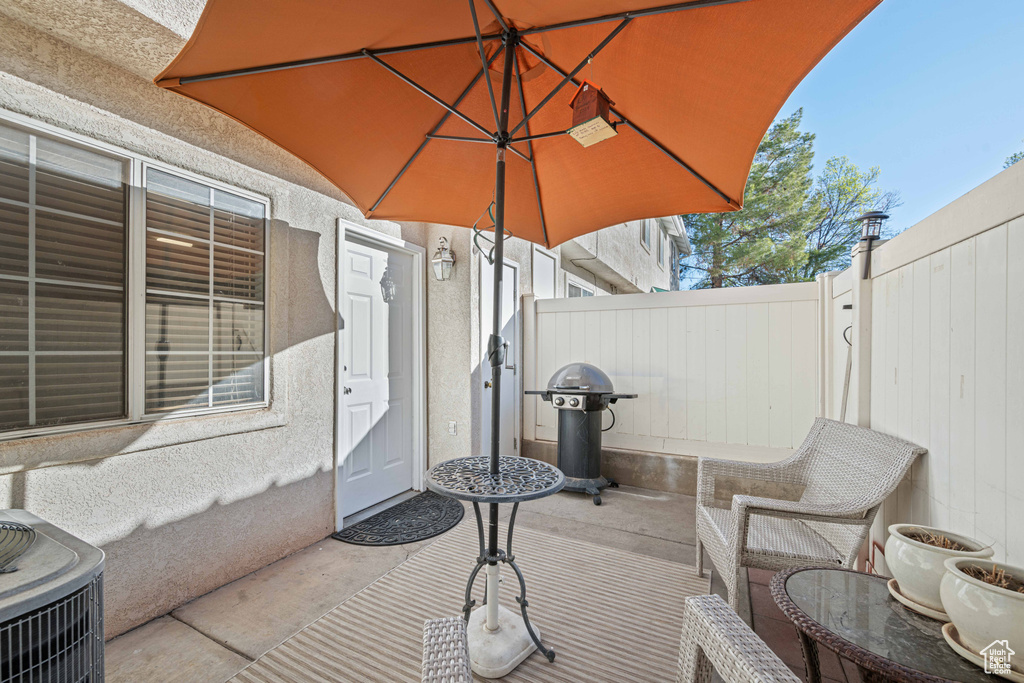 View of patio with central AC unit, grilling area, and fence