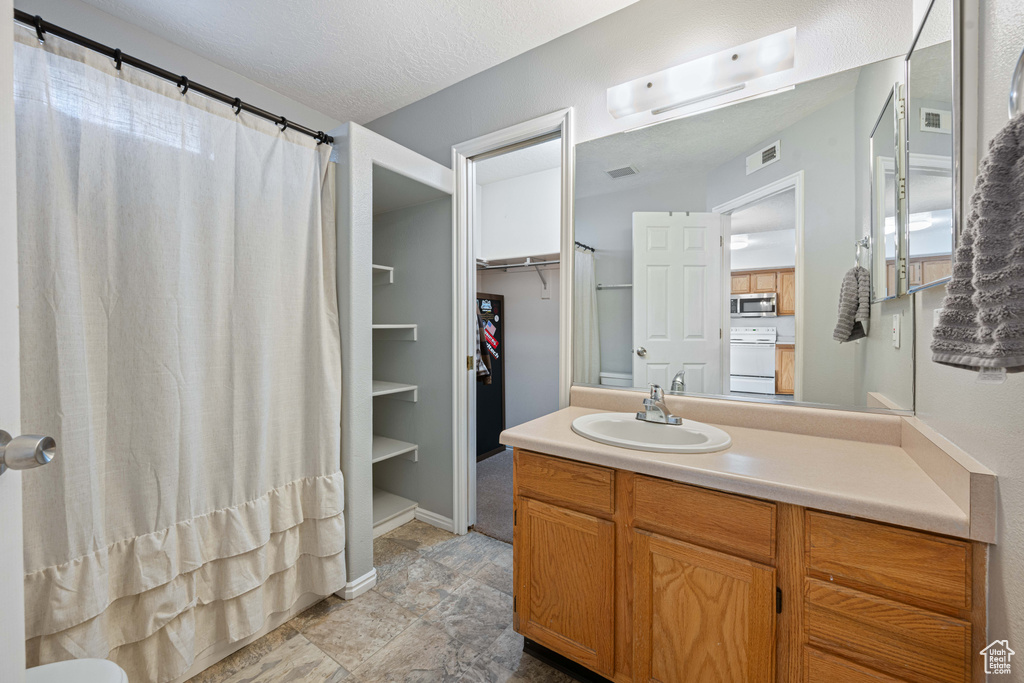 Full bath with visible vents, a shower with shower curtain, vanity, and a textured ceiling
