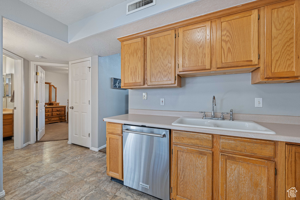 Kitchen with light countertops, visible vents, baseboards, a sink, and stainless steel dishwasher