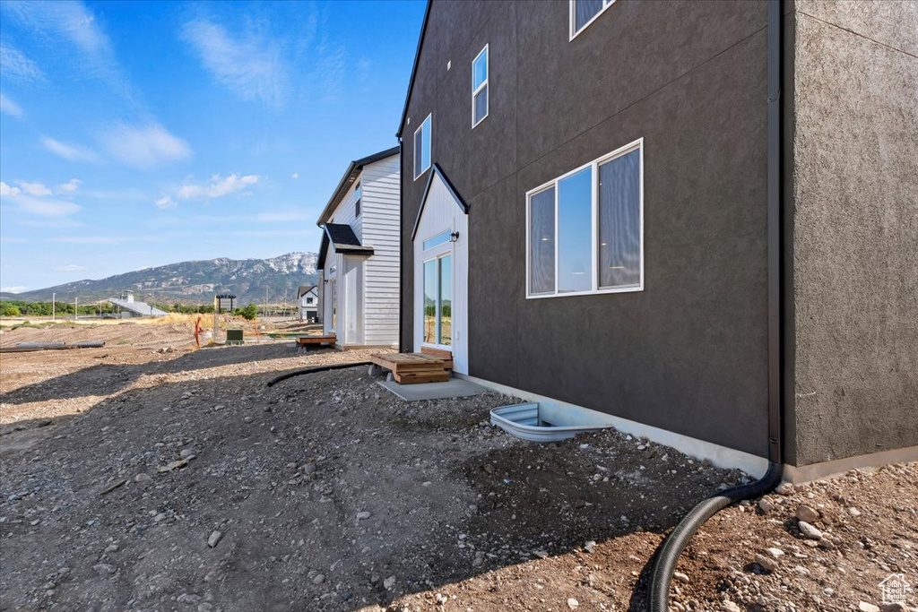 View of side of home with stucco siding, a mountain view, and entry steps
