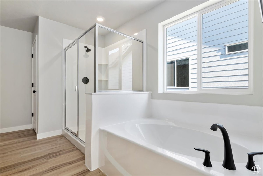 Bathroom with a stall shower, a garden tub, and wood finished floors