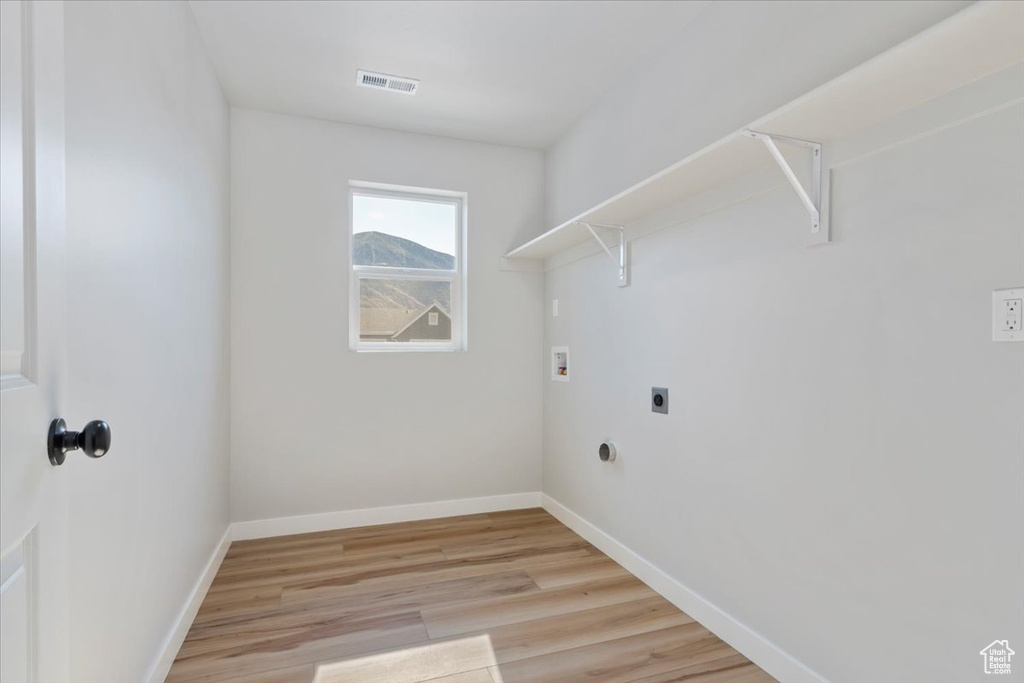Clothes washing area with light wood finished floors, washer hookup, hookup for an electric dryer, laundry area, and visible vents