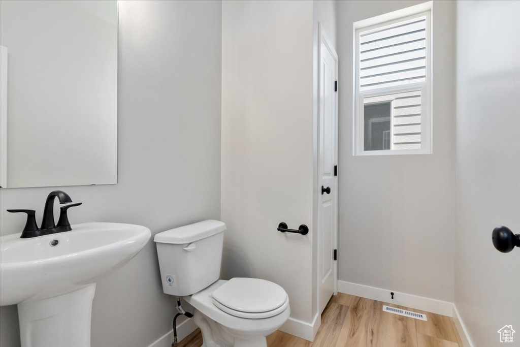Bathroom with visible vents, baseboards, toilet, wood finished floors, and a sink