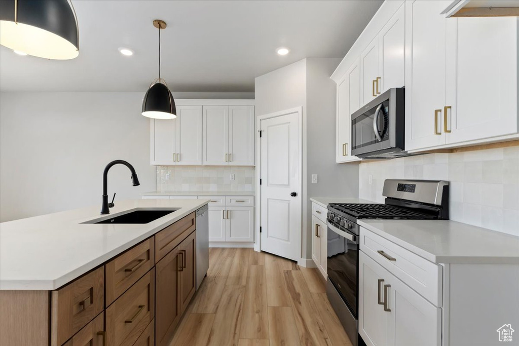 Kitchen featuring white cabinetry, light countertops, a sink, and appliances with stainless steel finishes