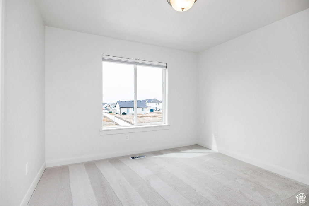 Carpeted empty room with baseboards and visible vents