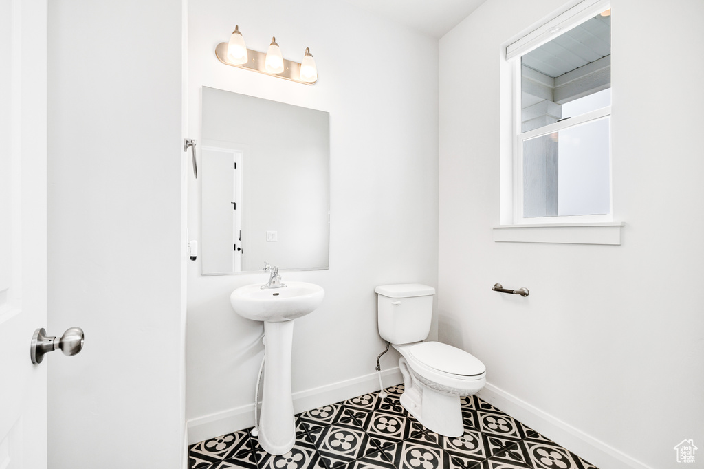Bathroom with baseboards, toilet, tile patterned floors, and a sink