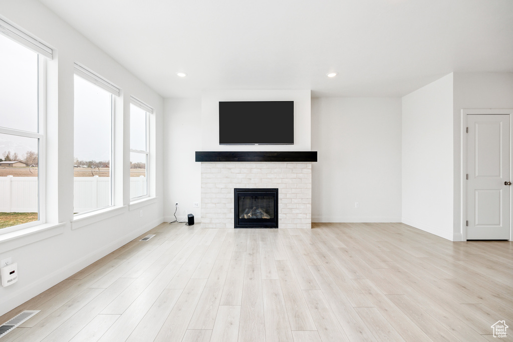 Unfurnished living room featuring recessed lighting, baseboards, light wood finished floors, visible vents, and a fireplace