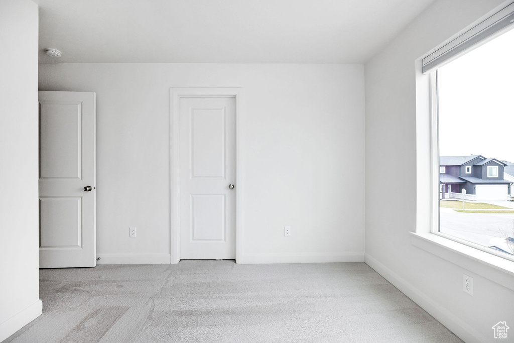 Unfurnished room with baseboards, a healthy amount of sunlight, and carpet