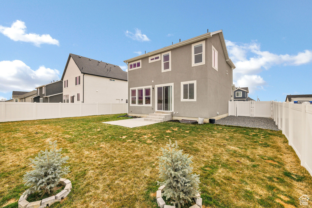 Back of house featuring a fenced backyard, a lawn, entry steps, and a patio area