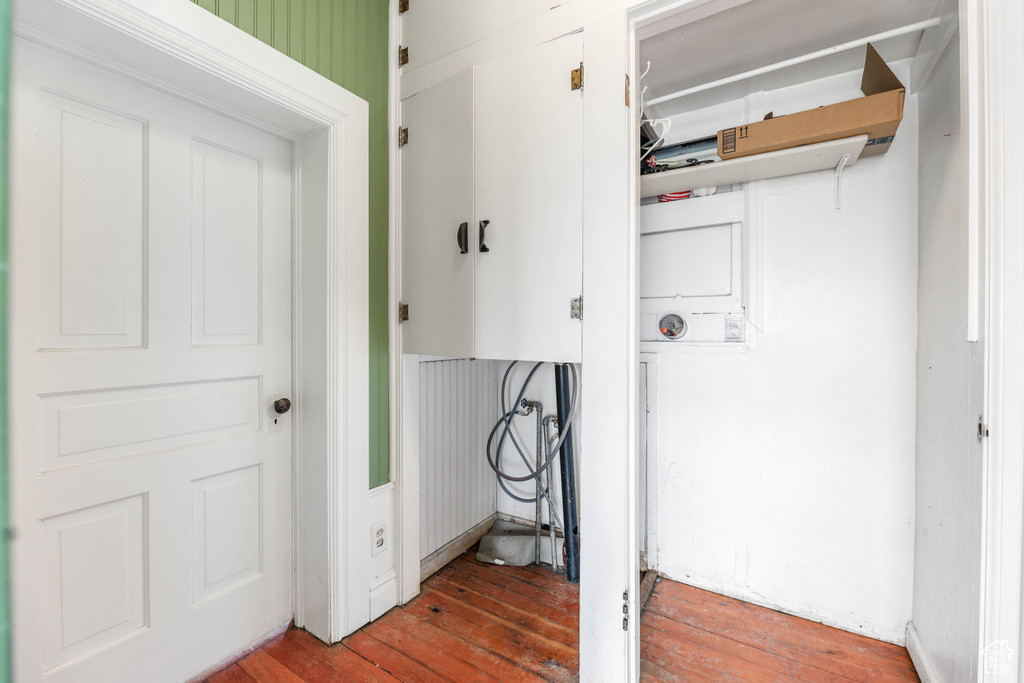 Clothes washing area with hardwood / wood-style flooring, laundry area, and stacked washer / drying machine