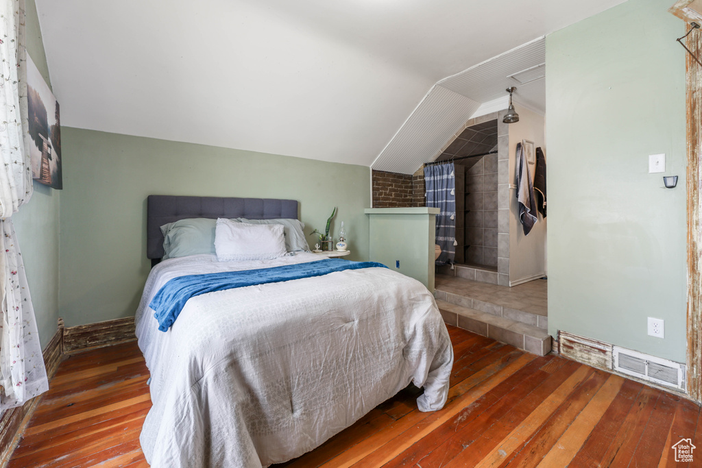 Bedroom featuring visible vents, vaulted ceiling, and wood-type flooring