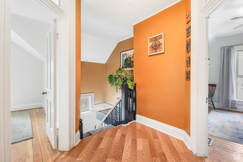 Corridor featuring an upstairs landing, hardwood / wood-style flooring, baseboards, and lofted ceiling