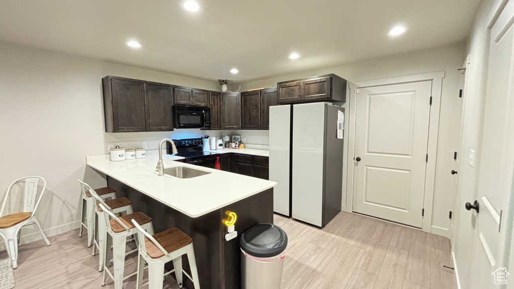 Kitchen featuring black appliances, light countertops, a sink, and dark brown cabinets