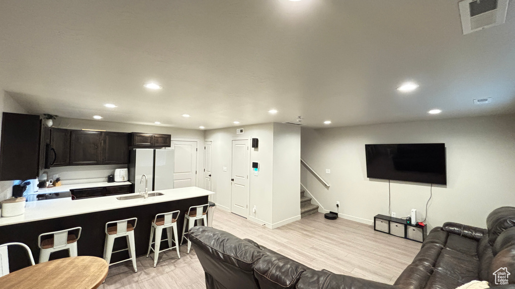 Living room with stairs, baseboards, visible vents, light wood-style floors, and recessed lighting