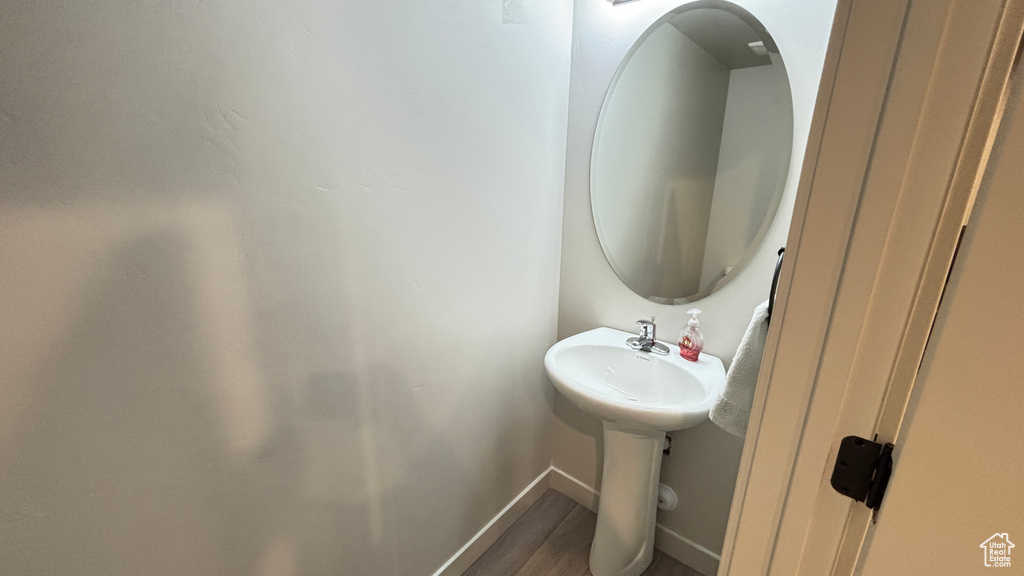 Bathroom featuring baseboards, wood finished floors, and a sink