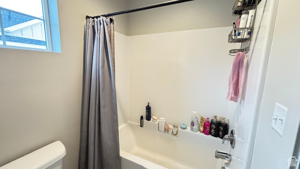 Full bathroom featuring toilet and shower / bath combo with shower curtain