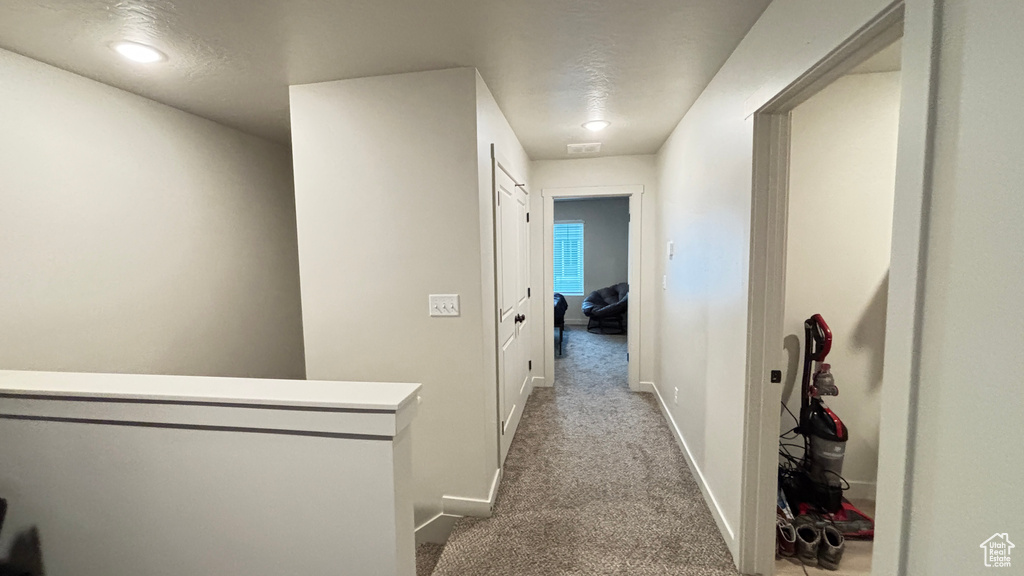 Hall with baseboards, carpet floors, and visible vents