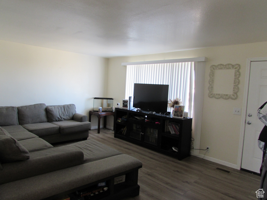 Living room with wood finished floors, visible vents, and baseboards