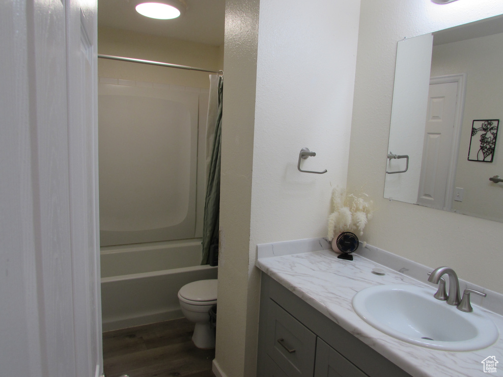 Full bathroom with vanity, toilet, wood finished floors, and shower / tub combo with curtain