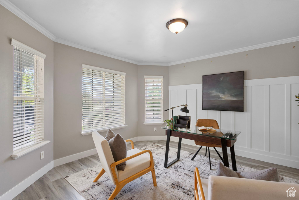 Home office with plenty of natural light, light wood-type flooring, crown molding, and a decorative wall