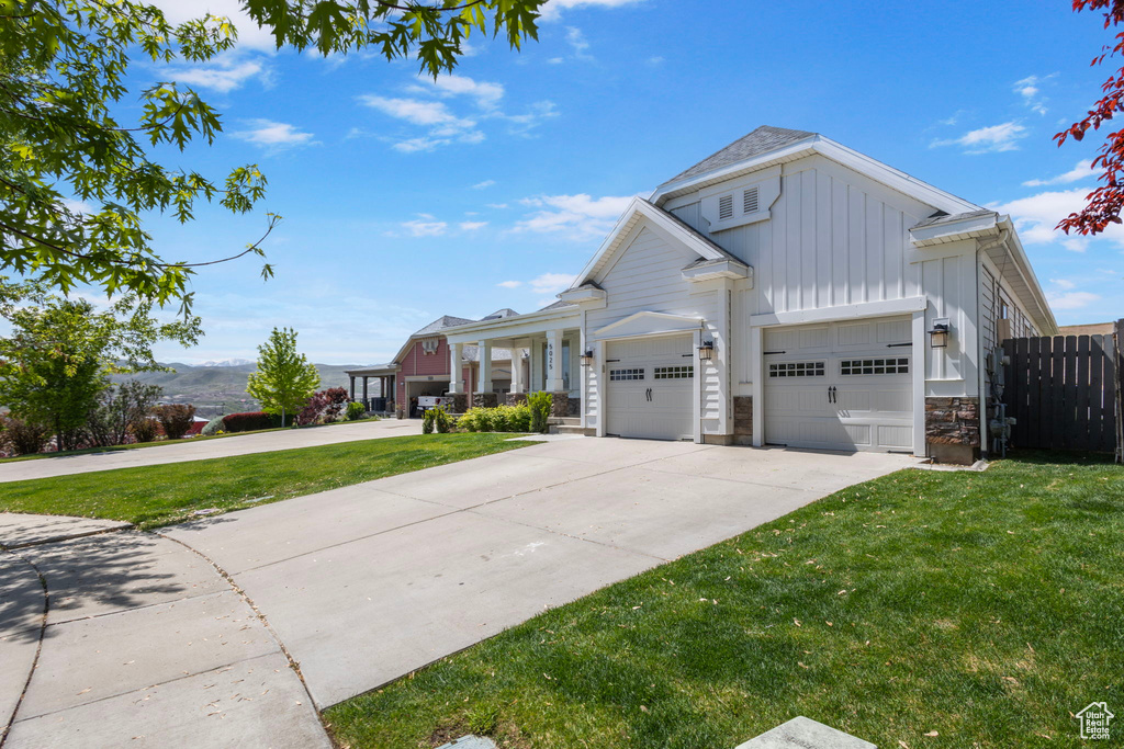 View of front of house featuring board and batten siding, driveway, a garage, and stone siding
