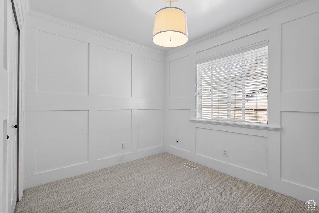 Carpeted spare room with a decorative wall and crown molding