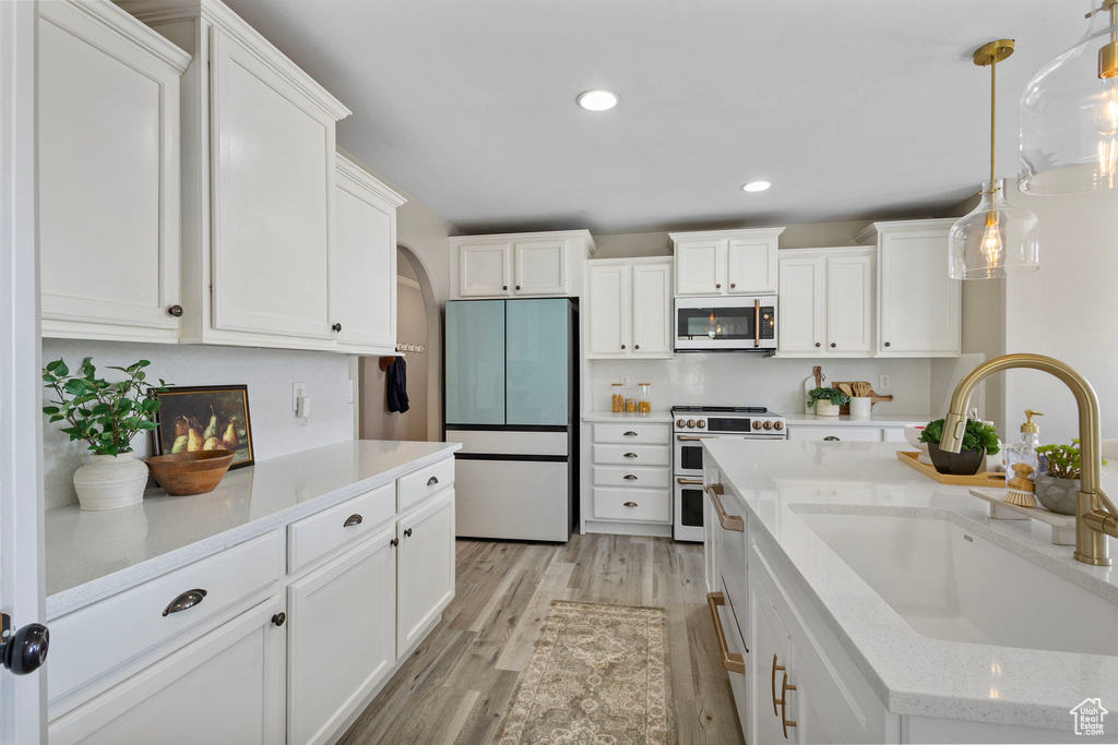Kitchen featuring refrigerator, double oven range, a sink, white cabinetry, and light wood-type flooring
