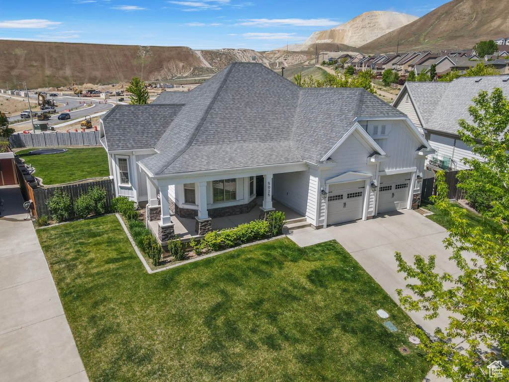 View of front facade with a shingled roof, driveway, an attached garage, and covered porch