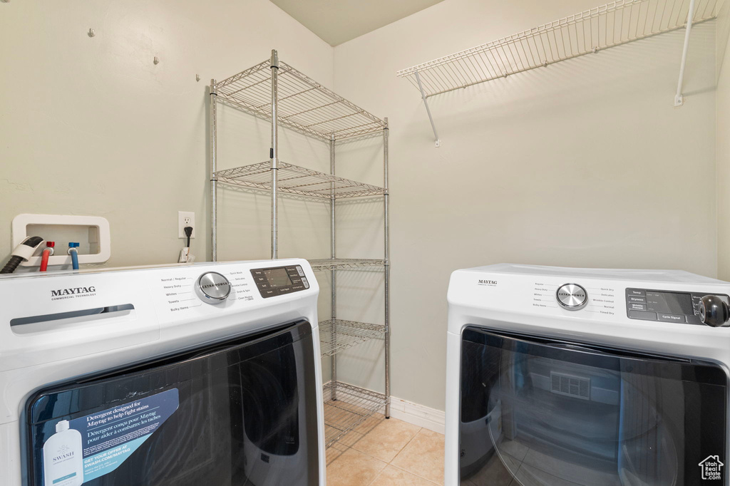 Laundry room with washer and dryer, baseboards, and tile patterned flooring