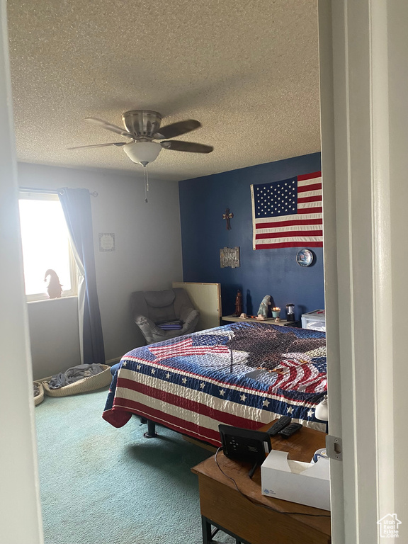Carpeted bedroom with ceiling fan and a textured ceiling