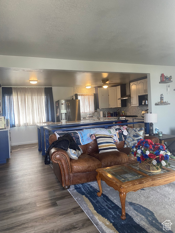 Living room with a textured ceiling, wood finished floors, and a ceiling fan