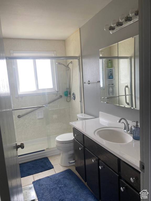 Full bathroom with toilet, a stall shower, tile patterned flooring, and vanity